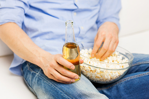 food, junk-food, unhealthy eating and people concept - close up of man with popcorn and beer bottle at home