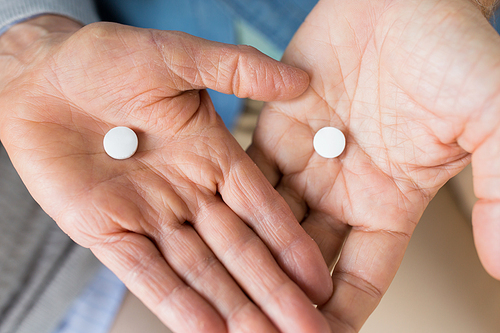 medicine, healthcare and people concept - close up of senior couple hands with pills