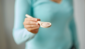food cooking, culinary and eating concept - close up of woman with sea salt on wooden spoon