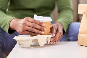 consumption and people concept - close up of man with takeaway coffee and food at home