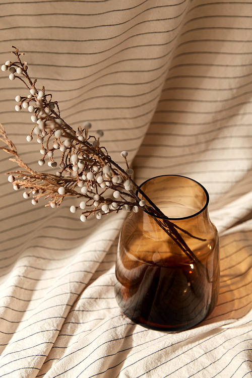 home improvement and decoration concept - still life of decorative dried flowers in brown glass vase with drapery