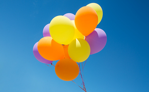 birthday, celebration and party decoration concept - close up of colorful balloons inflated with helium in blue sky