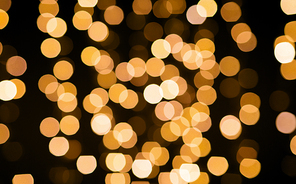 christmas and holidays concept - blurred golden lights bokeh on black background