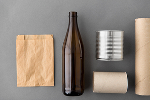 garbage disposal concept - different kind of glass, paper, metallic and plastic household waste on grey background