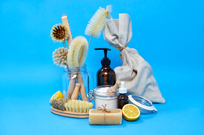natural cleaning stuff, sustainability and eco living concept - lemon halves, washing soda, bottle of vinegar with laundry and liquid soap and brushes on blue background