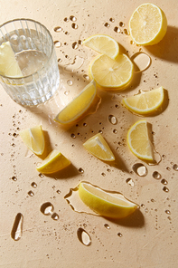 drink, detox and vitaminic concept - glass of water and lemon slices on wet table