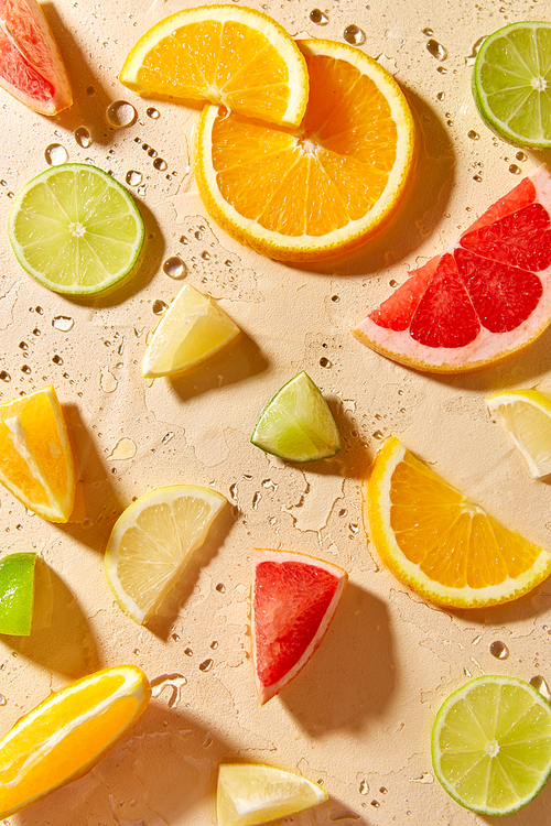 summer, vegetarian and vitaminic concept - slices of chopped different citrus fruits on wet surface