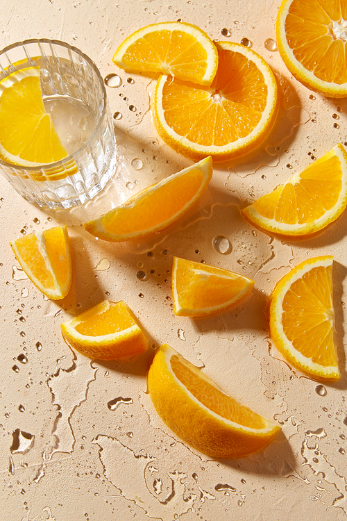 drink, detox and vitaminic concept - glass of water and orange slices on wet table