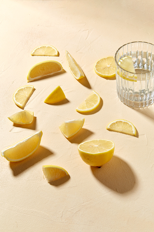 drink, detox and vitaminic concept - glass of water and lemon slices on table