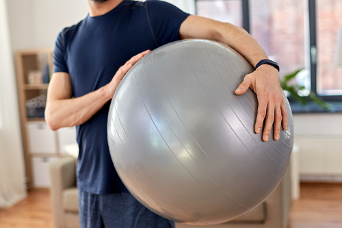sport and healthy lifestyle concept - close up of man with fitness ball at home
