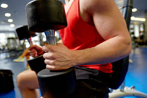 sport, fitness and healthy lifestyle concept - close up of man with dumbbells exercising in gym