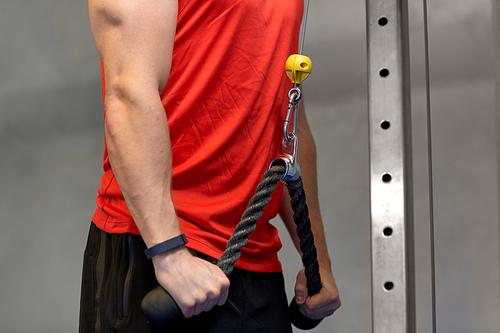 sport, fitness and bodybuilding concept - close up of man exercising with cable machine in gym