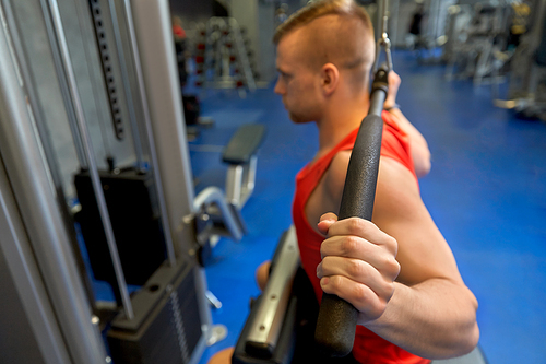 sport, fitness and bodybuilding concept - close up of man exercising with cable machine in gym