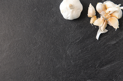 vegetable, food and culinary concept - garlic on slate stone background