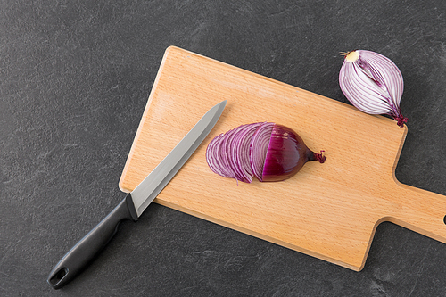 vegetable, food and culinary concept - chopped red onion and kitchen knife on wooden cutting board