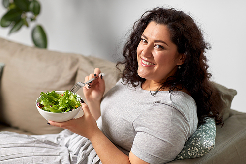 food, diet and people concept - happy smiling young woman eating vegetable salad at home