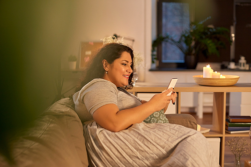 technology, leisure and people concept - happy smiling woman with smartphone at home in evening