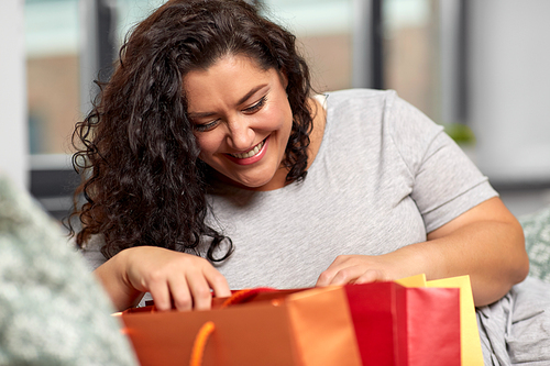 consumerism, people and sale concept - happy smiling young woman with shopping bags at home