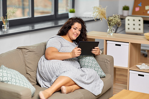 technology, leisure and people concept - happy smiling woman with tablet pc computer on sofa at home