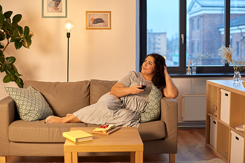 leisure and people concept - happy woman drinking red wine at home in evening