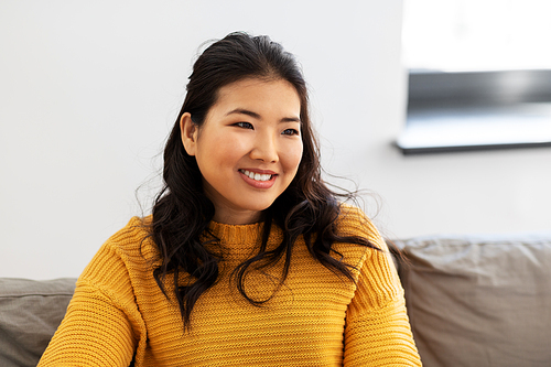 people, ethnicity and race concept - portrait of happy smiling asian young woman at home