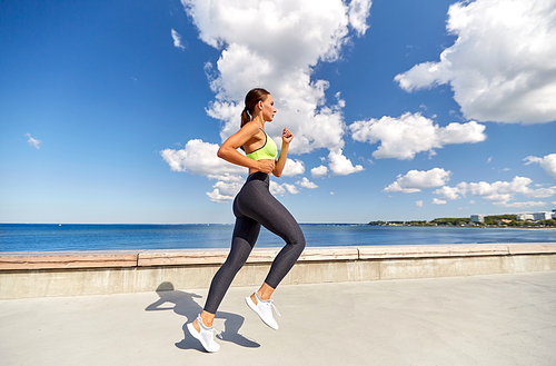 fitness, sport and healthy lifestyle concept - young woman running along sea promenade