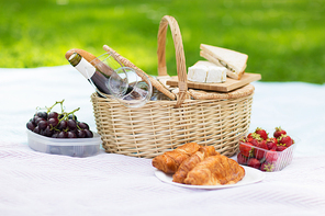 leisure concept - picnic basket, food and wine glasses on blanket at summer park