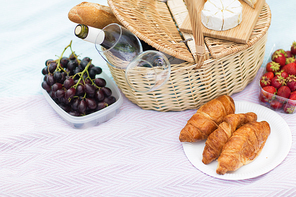leisure concept - picnic basket, food and wine glasses on blanket