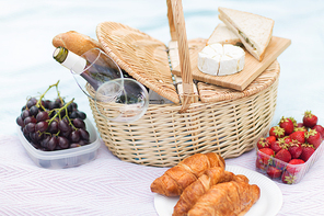 leisure concept - picnic basket, food and wine glasses on blanket