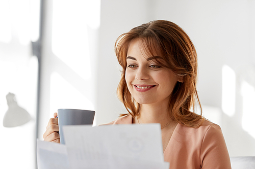 business and people concept - businesswoman with papers at working office and drinking coffee