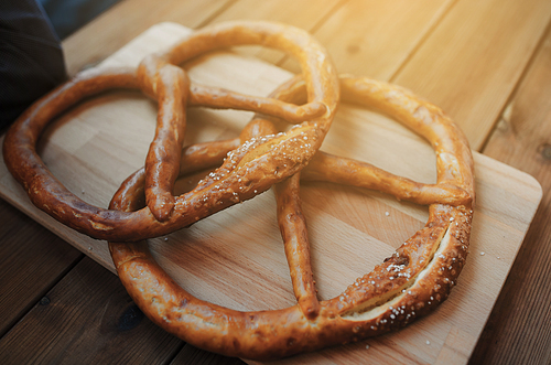food, baking, cooking and pastry concept - close up of two pretzels on wooden table