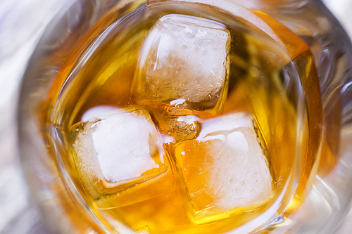 alcohol drinks and luxury concept - close up of ice in glass of whiskey