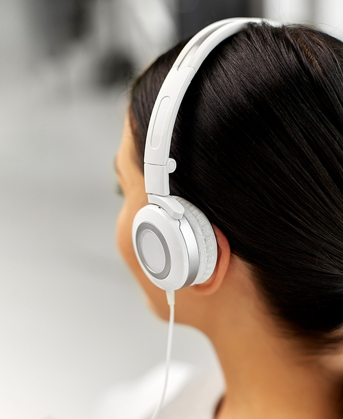 people, technology and audio equipment concept - close up of woman in headphones listening to music