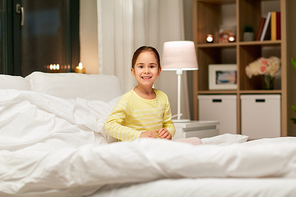 people, childhood and bedtime concept - happy little girl in bed at home bedroom at night