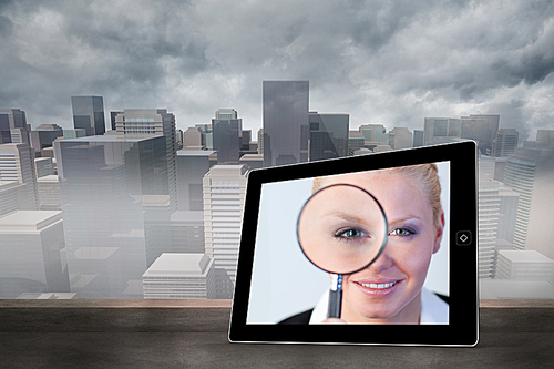 Composite image of businesswoman holding magnfying glass on tablet screen