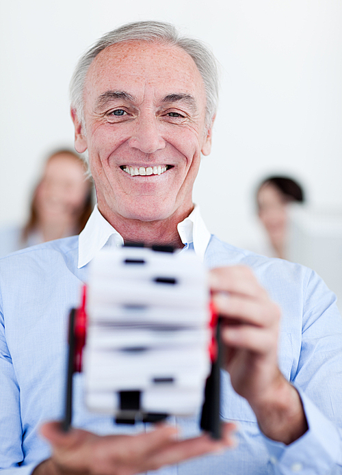 Smiling businessman consulting a business card holder