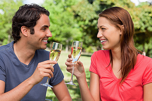 Two friends looking at each other while they are holding glasses of champagne  