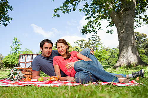 Two friends looking ahead while they hold glasses as they have a picnic