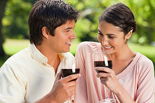 Two friends holding glasses of wine in a park