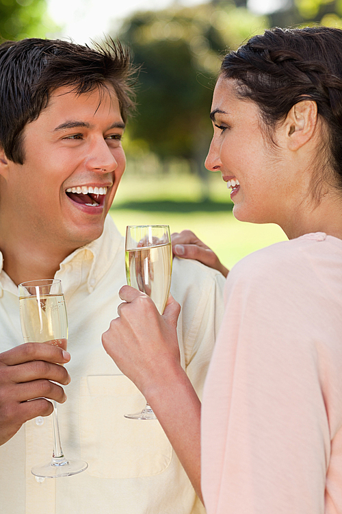 Two friends laughing while holding glasses of champagne