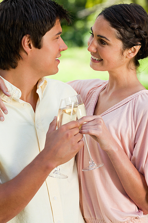 Two friends smiling while holding each other and touching glasses of champagne