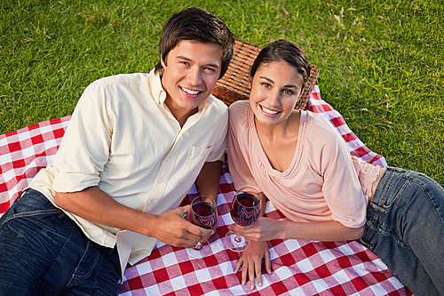 Two friends looking upwards while holding glasses of wine during a picnic