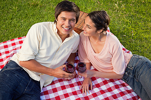 Woman looks at her friend while holding glasses of wine during a picnic