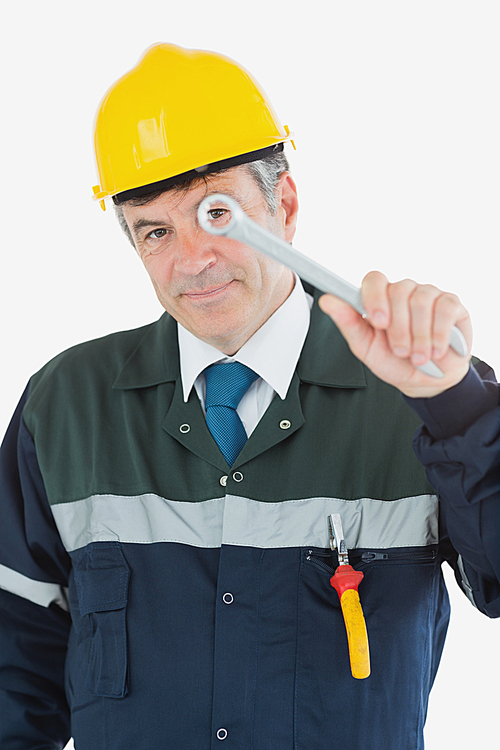 Mature repairman looking through wrench