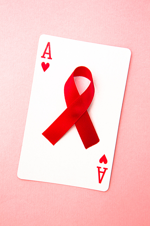 Red awareness ribbon lying on playing card