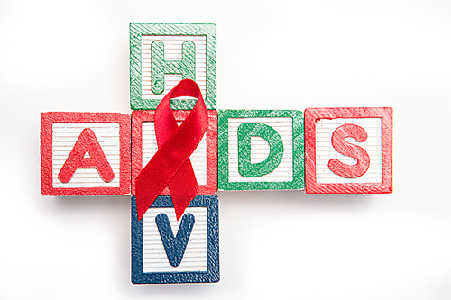 Wood blocks spelling aids and hiv in a cross shape with red awareness ribbon