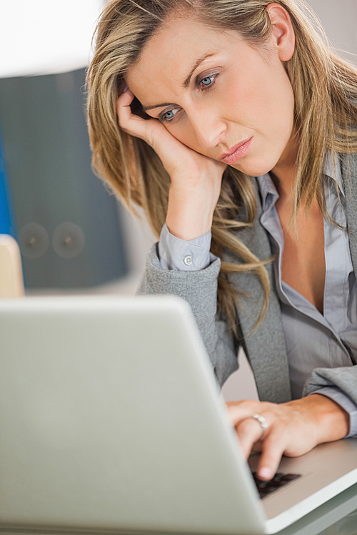 Jaded businesswoman looking at her laptop in an office