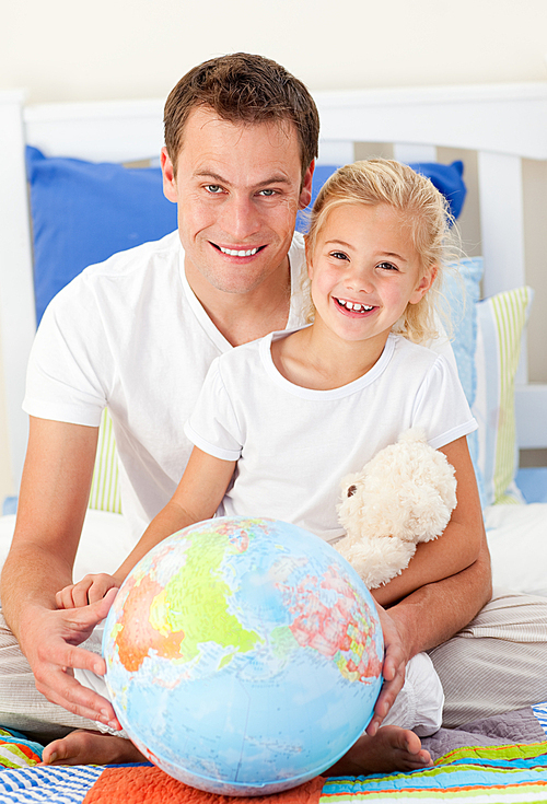 Attentive father and his daugther looking at a terrestrial globe