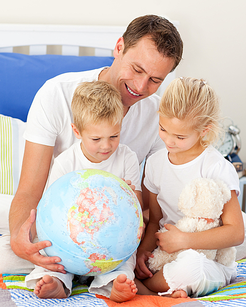 Adorable children and their father looking at a terrestrial globe