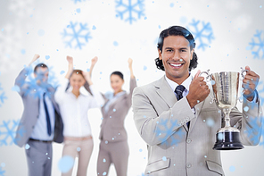 Close up of a man dressed in a suit smiling and holding a cup with people cheerin